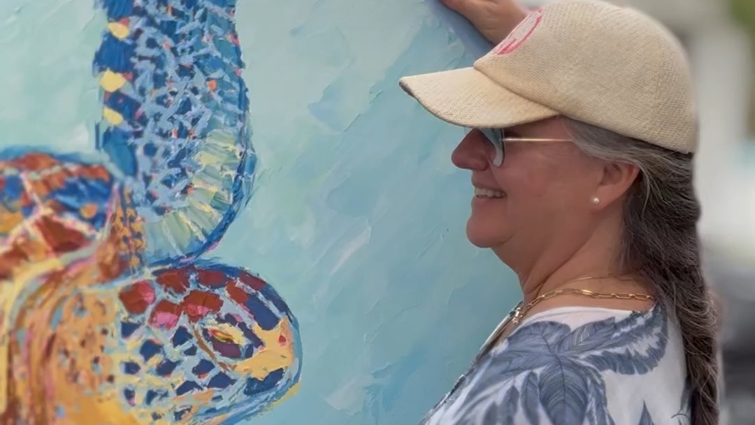Kelly Tracht carrying her sea turtle painting at an art show